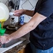 man häller fett från stekpanna i fett-tratt